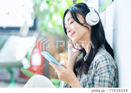 女性　ライフスタイル　スマホ　ヘッドフォン　音楽　リビング　ニューノーマル 77616548
