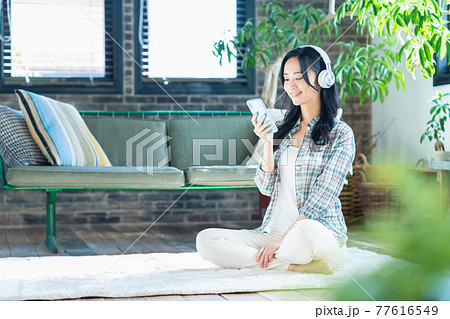 女性　ライフスタイル　スマホ　ヘッドフォン　音楽　リビング　ニューノーマル 77616549