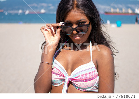 カナダのビーチで黒人系カナダ人の少女がサングラスをかける 77618671