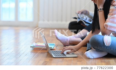 A young woman is using a computer laptop that putting on the sitting room ground floor. A young woman is using a computer laptop that putting on the sitting room ground floor. 77622300
