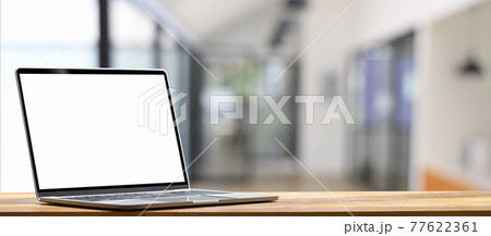 Laptop is putting on a wooden working desk over blurred background. 77622361