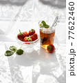 Cup of tea and wild strawberries on a white lace background 77622460