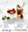Cup of tea and wild strawberries on a white lace background 77622462