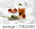 Cup of tea and wild strawberries on a white lace background 77622463