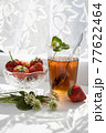 Cup of tea and wild strawberries on a white lace background 77622464