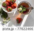 Cup of tea and wild strawberries on a white lace background 77622466