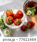 Cup of tea and wild strawberries on a white lace background 77622469