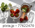 Cup of tea and wild strawberries on a white lace background 77622470
