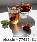 Cup of tea and wild strawberries on a white background 77622481