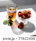 Cup of tea and wild strawberries on a white background 77622498