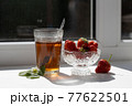 Cup of tea and wild strawberries on a white background 77622501