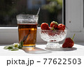 Cup of tea and wild strawberries on a white background 77622503