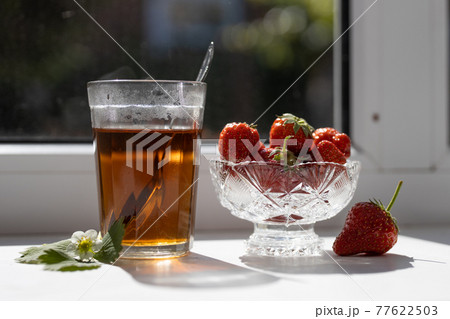 Cup of tea and wild strawberries on a white background Cup of tea and wild strawberries on a white background 77622503