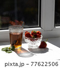 Cup of tea and wild strawberries on a wooden background 77622506