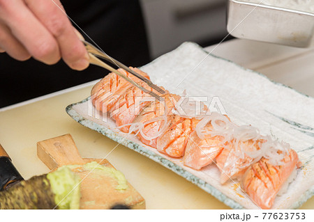 炙りサーモンの握り寿司の盛り付けをする職人の手元 炙りサーモンの握り寿司の盛り付けをする職人の手元 77623753