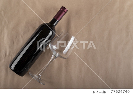 Wine bottle and glass on a brown background. Wine drinking culture concept. Space for text. Wine bottle and glass on a brown background. Wine drinking culture concept. Space for text. 77624740