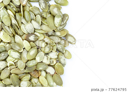 Close-up background texture of green pumpkin seeds on a white background. Space for text. Close-up background texture of green pumpkin seeds on a white background. Space for text. 77624795