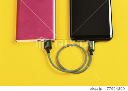 Smartphone Charging with Pink Power Bank on Yellow Background 77624800