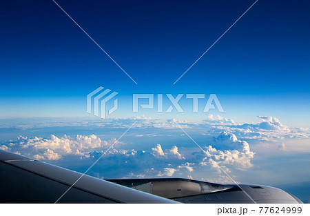 飛行機で見る雲の上に広がる青い景色 77624999