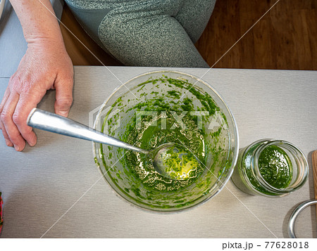 Woman preparing fresh bio pesto from spring leaves of wild bear garlic herb. Woman preparing fresh bio pesto from spring leaves of wild bear garlic herb. 77628018