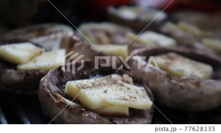 Grilled mushrooms with cheese, tomatoes  and eggplant on the hot flaming charcoal grill. Champignon white mushrooms, onions and tomatoes grilled on grill with hot coal 77628135