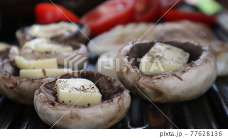 Grilled mushrooms with cheese, tomatoes and eggplant on the hot flaming charcoal grill. Champignon white mushrooms, onions and tomatoes grilled on grill with hot coal Grilled mushrooms with cheese, tomatoes and eggplant on the hot flaming charcoal grill. Champignon white mushrooms, onions and tomatoes grilled on grill with hot coal 77628136