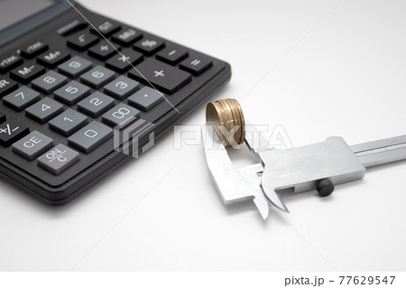 Black Calculator and Coin in Caliper. Business and financial Black Calculator and Coin in Caliper. Business and financial 77629547