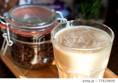 Cappuccino in a double glass cup and jar with coffee beans on wooden plate Cappuccino in a double glass cup and jar with coffee beans on wooden plate 77629606