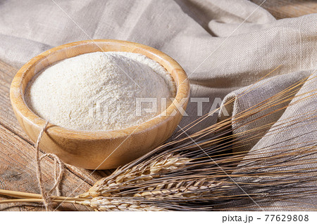 Whole wheat durum flour in wooden bowl with spikelets Whole wheat durum flour in wooden bowl with spikelets 77629808