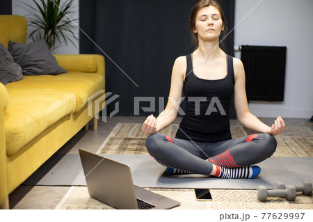 Young healthy woman practicing yoga at home sitting in lotus pose meditating Young healthy woman practicing yoga at home sitting in lotus pose meditating 77629997