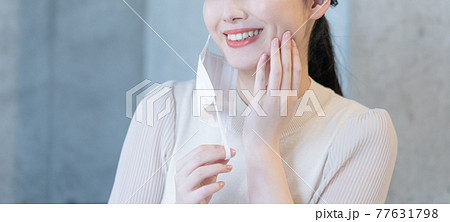 マスクを耳にかけて微笑む若い女性　バナーサイズ 77631798