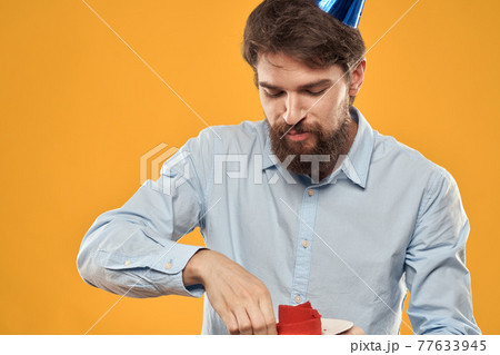 Man with cake on yellow background birthday party hat cropped view Man with cake on yellow background birthday party hat cropped view 77633945
