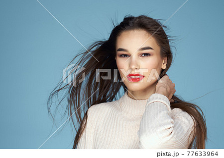 Brunette in a white sweater red lips charm long hair blue background Brunette in a white sweater red lips charm long hair blue background 77633964