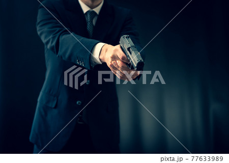 拳銃を構えるスーツの人物 77633989
