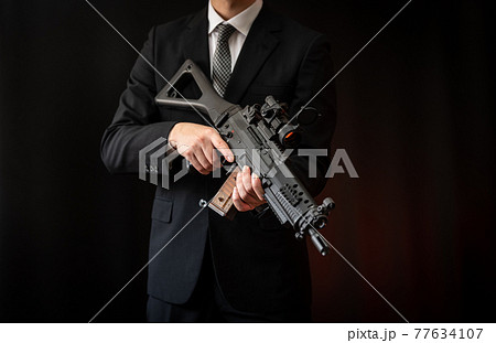 A Person In A Suit Holding An Assault Rifle Stock Photo