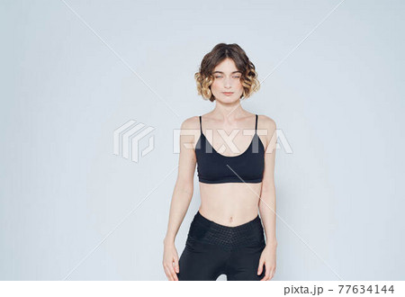 Woman in leggings doing exercises on a light background cropped view of fitness gymnastics 77634144