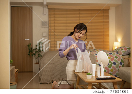 帰宅後に買い物袋を確認する女性 77634362