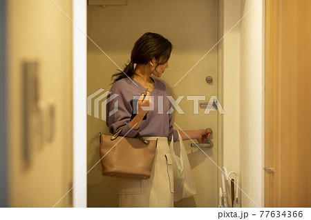 ドアの鍵を閉める女性 ドアの鍵を閉める女性 77634366