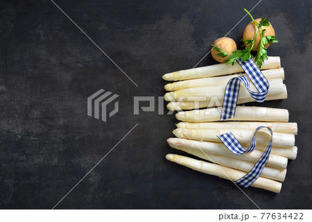 Fresh Bavarian white asparagus from Schrobenhausen on a shabby baking sheet with copy space 77634422