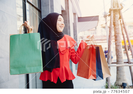 Shopping Arab Muslim adult woman in veil hijab clothes holding bags walk in city street enjoy happy smile. Shopping Arab Muslim adult woman in veil hijab clothes holding bags walk in city street enjoy happy smile. 77634507