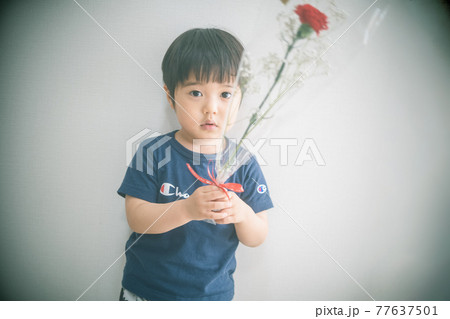 カーネーションの花束を持つ三歳児 77637501
