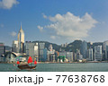 香港・高層ビル街をバックにヴィクトリア・ハーバーを往くジャンク船 77638768