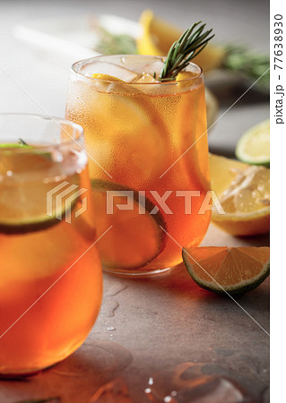 Iced tea with lemon, lime and ice garnished with rosemary twigs. 77638930