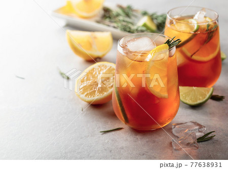 Iced tea with lemon, lime and ice garnished with rosemary twigs. 77638931