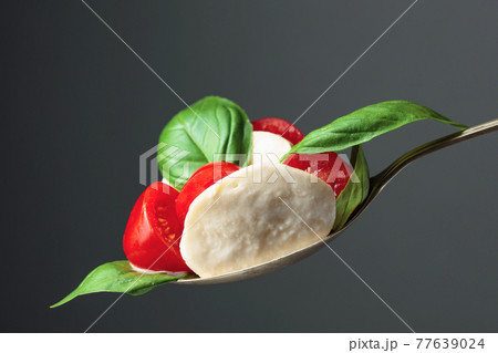 Mozzarella with tomato and basil on a dark background. 77639024