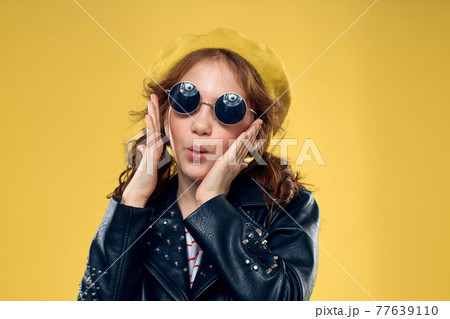 Cheerful little girl in sunglasses and hat lifestyle studio yellow background fashion Cheerful little girl in sunglasses and hat lifestyle studio yellow background fashion 77639110