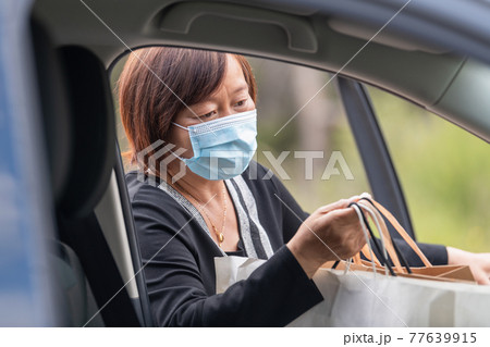 Close up of mature asian woman putting shopping bags inside her car Close up of mature asian woman putting shopping bags inside her car 77639915
