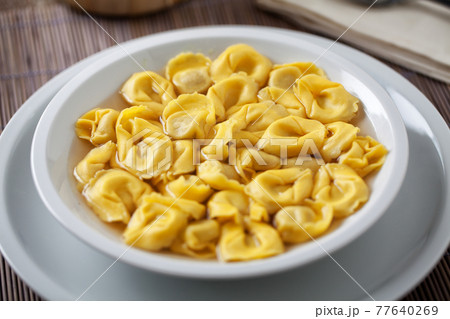 Italian Tortellini In broth on a plate. 77640269