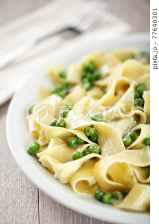 Tagliatelle pasta with cream and peas on a plate. 77640301