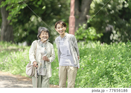 公園で散歩するシニア女性と介護士 公園で散歩するシニア女性と介護士 77656186